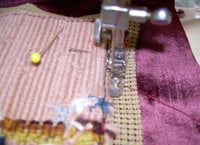 Sewing the needlepoint canvas to the cushion backing.